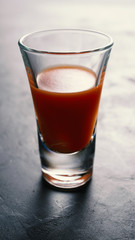 Tomato juice in a vodka glass on black concrete