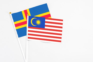 Malaysia and Aland Islands stick flags on white background. High quality fabric, miniature national flag. Peaceful global concept.White floor for copy space.