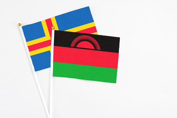 Malawi and Aland Islands stick flags on white background. High quality fabric, miniature national...