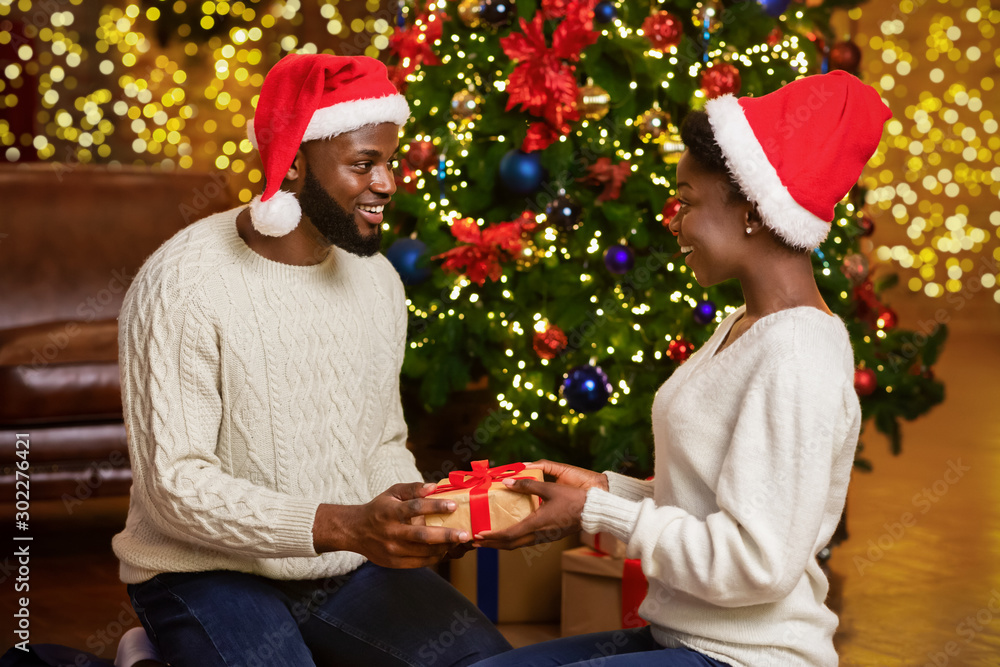 Sticker Romantic black couple exchanging presents near Christmas tree