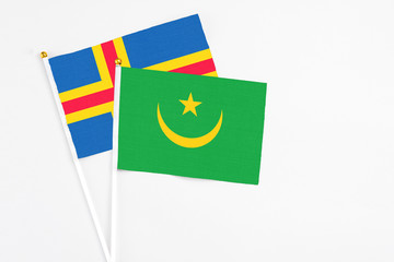 Mauritania and Aland Islands stick flags on white background. High quality fabric, miniature national flag. Peaceful global concept.White floor for copy space.