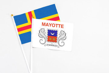 Mayotte and Aland Islands stick flags on white background. High quality fabric, miniature national flag. Peaceful global concept.White floor for copy space.