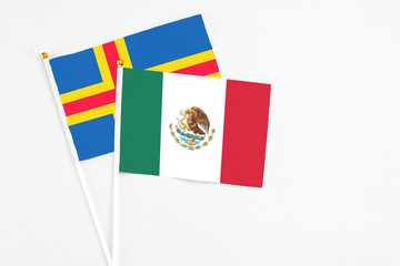 Mexico and Aland Islands stick flags on white background. High quality fabric, miniature national flag. Peaceful global concept.White floor for copy space.