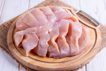 Chicken fillet on a cutting board for cooking baked breast with tomatoes and cheese