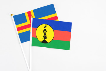 New Caledonia and Aland Islands stick flags on white background. High quality fabric, miniature national flag. Peaceful global concept.White floor for copy space.