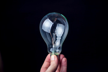 Light bulb in hand in front of black background. Technology or idea concept