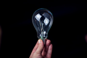 Light bulb in hand in front of black background. Technology or idea concept