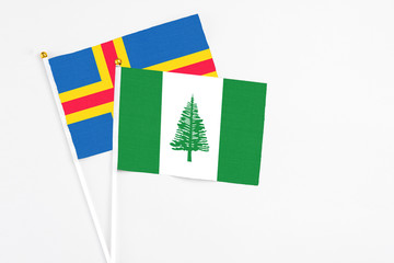 Norfolk Island and Aland Islands stick flags on white background. High quality fabric, miniature national flag. Peaceful global concept.White floor for copy space.