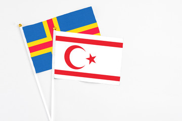 Northern Cyprus and Aland Islands stick flags on white background. High quality fabric, miniature national flag. Peaceful global concept.White floor for copy space.