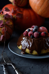 Healthy homemade dessert. Traditional steam pudding with chocolate glaze and berries and winter squashes on black background