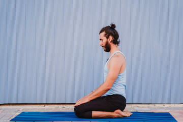 man in the city practicing yoga sport. blue background. healthy lifestyle