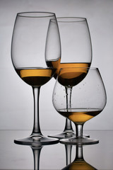 Wine glass goblets on long legs. Nearby is a glass on a short leg. They have a small amount of alcohol.