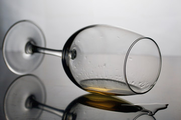 Wine glass on a long leg. Lies on its side, photographed in the light. It has a small amount of alcohol.