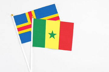 Senegal and Aland Islands stick flags on white background. High quality fabric, miniature national flag. Peaceful global concept.White floor for copy space.