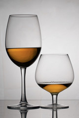Wine glass goblets on long and short legs. They stand nearby. They have a small amount of alcohol.