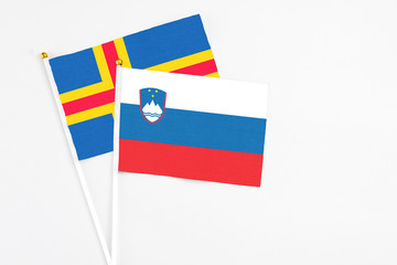 Slovenia and Aland Islands stick flags on white background. High quality fabric, miniature national flag. Peaceful global concept.White floor for copy space.