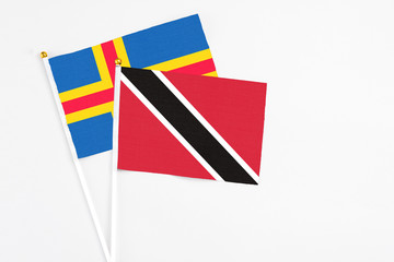 Trinidad And Tobago and Aland Islands stick flags on white background. High quality fabric, miniature national flag. Peaceful global concept.White floor for copy space.
