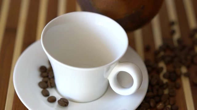 Arabic coffee is poured into a white cup.