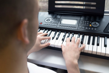 Fototapeta na wymiar Pianist is playing the piano. Person, guy or man holding hands, fingers on keys of a digital musical modern electronic synthesizer. Piano training, music lesson.