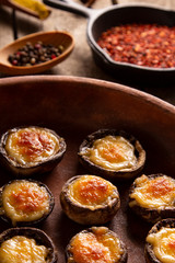 Roasted mushrooms with vegetables and parsley under melting cheese