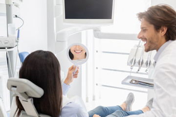 Sattisfied client of dental clinic smiling at mirror
