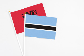 Botswana and Albania stick flags on white background. High quality fabric, miniature national flag. Peaceful global concept.White floor for copy space.