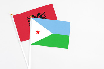 Djibouti and Albania stick flags on white background. High quality fabric, miniature national flag. Peaceful global concept.White floor for copy space.