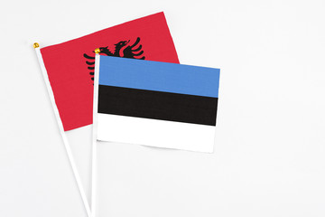 Estonia and Albania stick flags on white background. High quality fabric, miniature national flag. Peaceful global concept.White floor for copy space.