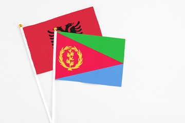 Eritrea and Albania stick flags on white background. High quality fabric, miniature national flag. Peaceful global concept.White floor for copy space.