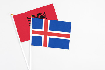 Iceland and Albania stick flags on white background. High quality fabric, miniature national flag. Peaceful global concept.White floor for copy space.