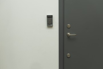 Close up view of grey metal door with digital code lock to the left. Security concept, 