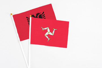 Isle Of Man and Albania stick flags on white background. High quality fabric, miniature national flag. Peaceful global concept.White floor for copy space.