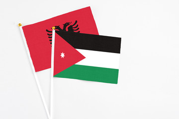 Jordan and Albania stick flags on white background. High quality fabric, miniature national flag. Peaceful global concept.White floor for copy space.