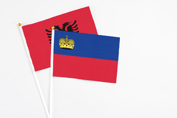 Liechtenstein and Albania stick flags on white background. High quality fabric, miniature national flag. Peaceful global concept.White floor for copy space.