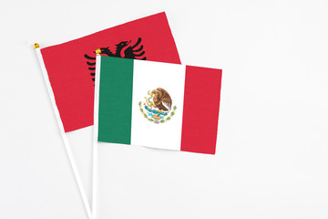 Mexico and Albania stick flags on white background. High quality fabric, miniature national flag. Peaceful global concept.White floor for copy space.