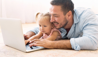 Millennial father and daughter using laptop together