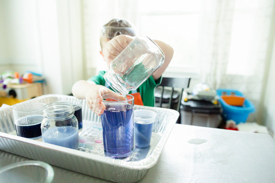 Anonymous child pours blue liquid into glass during science experiment