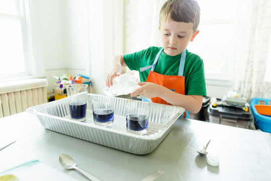 Elementary age male student pours liquid during science experiment