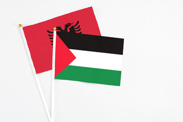 Palestine and Albania stick flags on white background. High quality fabric, miniature national flag. Peaceful global concept.White floor for copy space.