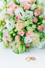 beautiful wedding bouquet and gold wedding rings on white surfac