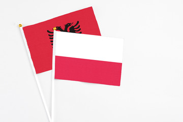 Poland and Albania stick flags on white background. High quality fabric, miniature national flag. Peaceful global concept.White floor for copy space.