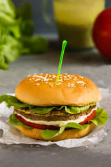 Vegetarian Burger with chickpeas, fresh cucumber, tomato, salad and sour cream sauce. The concept of healthy eating. An alternative to the usual hamburger. Vertical.