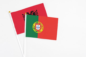 Portugal and Albania stick flags on white background. High quality fabric, miniature national flag. Peaceful global concept.White floor for copy space.