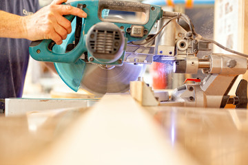 Shipwright cutting a piece of wood with a circular saw machine
