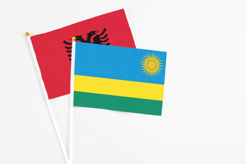 Rwanda and Albania stick flags on white background. High quality fabric, miniature national flag. Peaceful global concept.White floor for copy space.