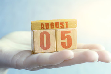 august 5th. Day 5 of month,Handmade wood cube with date month and day on female palm summer month, day of the year concept