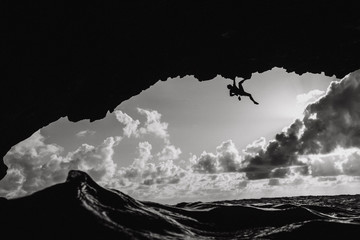 Man climbing above the ocean in a volcanic cave