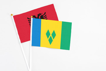 Saint Vincent And The Grenadines and Albania stick flags on white background. High quality fabric, miniature national flag. Peaceful global concept.White floor for copy space.