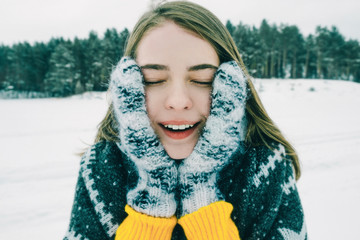 Girl face in warm knitted mittens