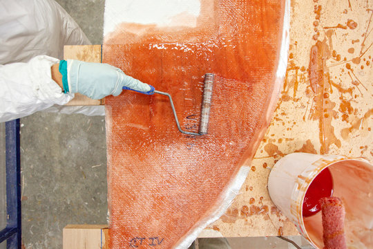 one person applying fiberglass on a mold in a boat building factory